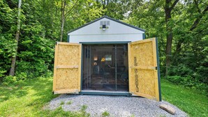 A small, single-story building with a sloped roof, a large glass door, and wooden construction. - Hunley Haven Retreat (Cincinnati)