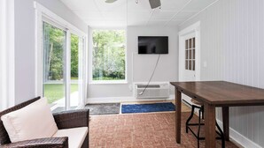 A room with a ceiling fan, a flat-screen TV mounted on the wall, a dining table, and a sofa. - Hunley Haven Retreat (Cincinnati)