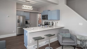 Una cocina moderna con gabinetes grises, electrodomésticos de acero inoxidable y una isla blanca con taburetes de bar.