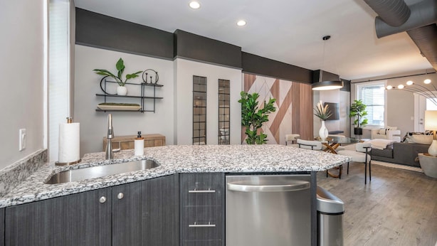 A modern kitchen with a granite countertop, stainless steel appliances, and a built-in dishwasher. - Queen City Views Suites (Cincinnati)