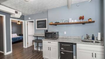 A compact kitchen with white cabinets, a microwave, and a dishwasher.