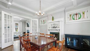 A spacious dining room with a large wooden table and chairs, a chandelier, and a fireplace. - Urban Elegance Getaway (Columbus)