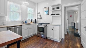 A modern kitchen with white cabinetry, a stainless steel dishwasher, and a double oven.