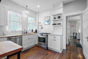 A modern kitchen with white cabinetry, a stainless steel dishwasher, and a double oven. - Urban Elegance Getaway (Columbus)