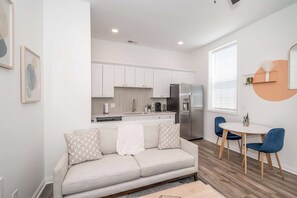 A modern apartment with a kitchenette, a sofa with patterned cushions, and a dining area with blue chairs. - Heart of Covington | 5-min Drive to Downtown Cincy (Covington)