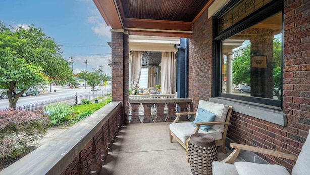 Een balkon met uitzicht op een straat, een bakstenen muur en een raam met vlinderdecoratie.