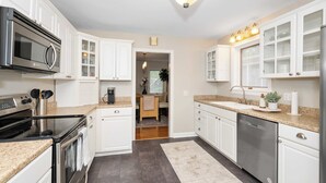 A modern kitchen with white cabinetry, stainless steel appliances, and a granite countertop. - The Cincinnati Charm (Cincinnati)