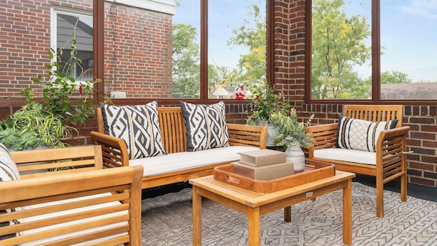A sunroom with wooden furniture, large windows, and a brick wall. - The Cincinnati Charm (Cincinnati)
