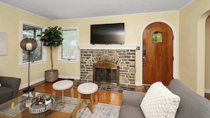 A living room with a stone fireplace, a flat-screen TV mounted above it, and a large plant. - The Cincinnati Charm (Cincinnati)