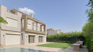 Une maison moderne à deux étages, dotée d’une piscine, d’un patio couvert et d’une pelouse bien entretenue.