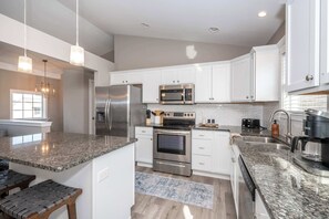 A modern kitchen with white cabinets, stainless steel appliances, granite countertops, and a built-in oven.