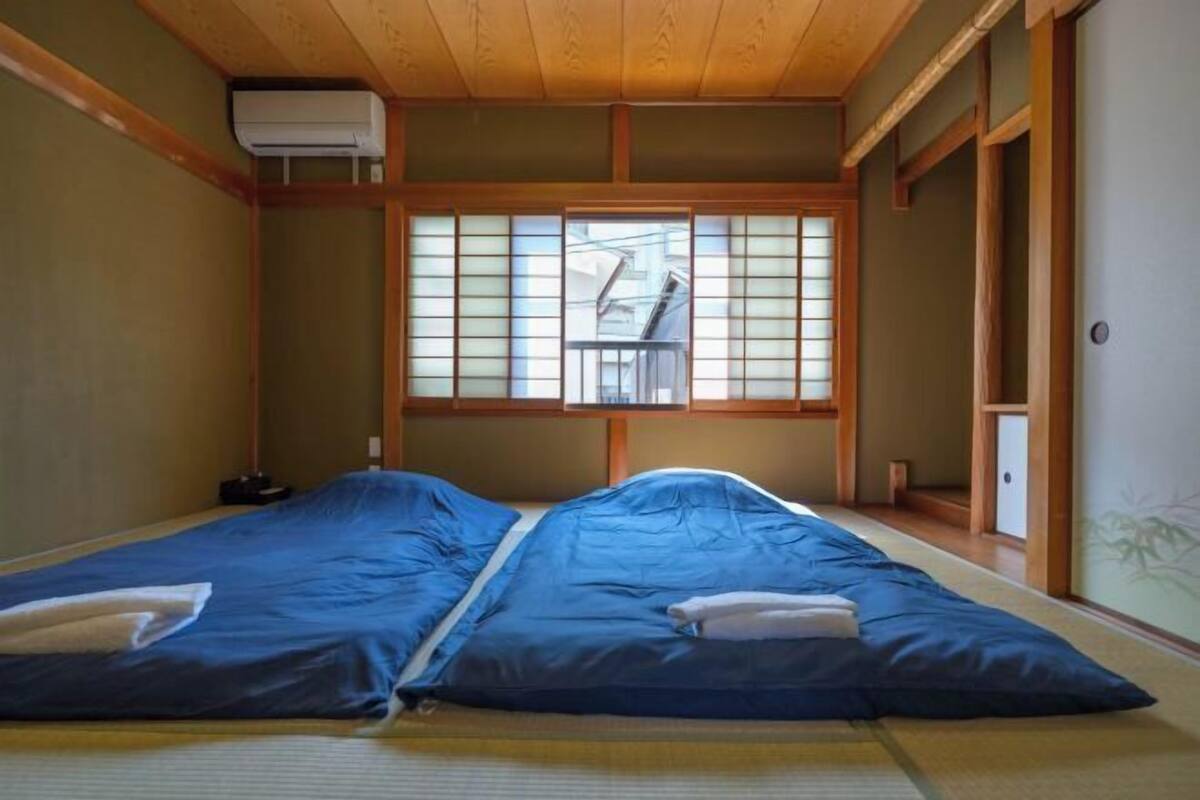 A traditional Japanese room with tatami flooring, a sliding door, and a window with shoji screens.