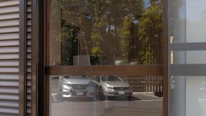 Blick durch ein Fenster, Spiegelung von parkenden Autos und Bäumen.