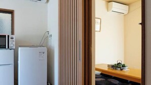 Eine kleine Küche mit Mikrowelle, Kühlschrank und einer Holzwand.