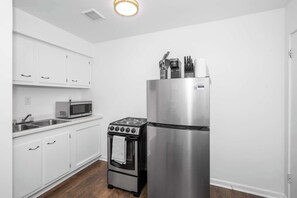A kitchen with white cabinets, a stainless steel refrigerator, a microwave, and an oven.