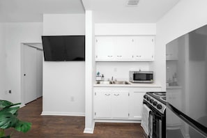 Une cuisine de taille réduite avec des meubles blancs, un four à micro-ondes et une cuisinière.