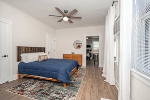 A bedroom with a bed, a ceiling fan, a dresser, and a rug.