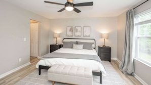 A bedroom with a bed, bedside tables, a ceiling fan, and a window with curtains. - Poolside Paradise Near the Ark (Walton)