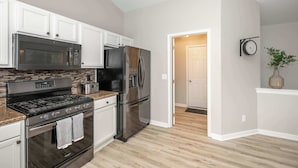 A modern kitchen with stainless steel appliances, white cabinetry, and a wooden floor. - Poolside Paradise Near the Ark (Walton)
