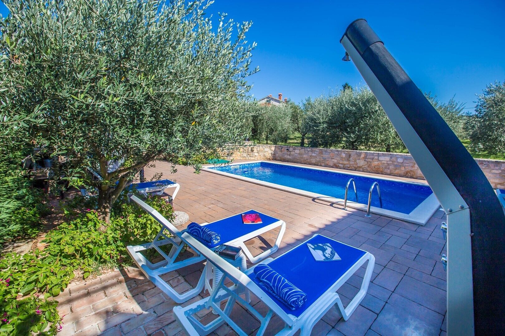 Une piscine avec deux chaises longues et un mur de pierre en arrière-plan.