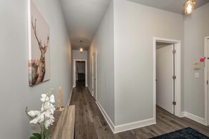 A hallway with wooden flooring, white walls, and a door on the right.