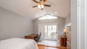 A bedroom with a bed, desk, chair, dresser, and a ceiling fan. - Suites on Main 1 (Covington)