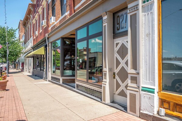 A row of brick buildings with large windows and a sidewalk.