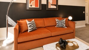 A modern living room with a sofa, a floor lamp, and two framed abstract artworks on the wall.