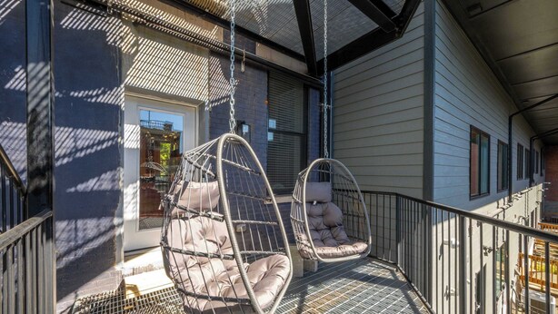 A balcony with two hanging chairs and a metal railing.