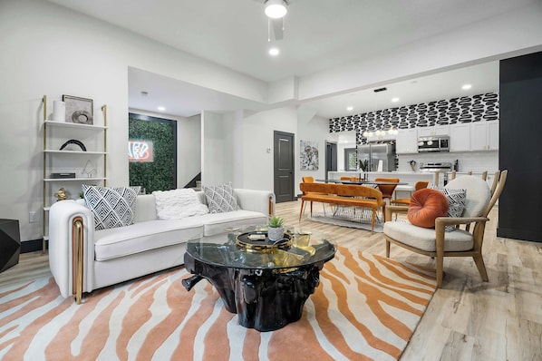A modern living room with a white sofa, a glass coffee table, and a zebra-patterned rug.