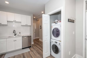 Une cuisine compacte avec des meubles blancs, un lave-vaisselle et un lave-linge.