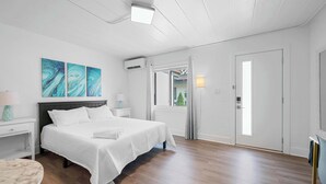 A bedroom with a bed, bedside tables, a nightstand, a window, and a door.