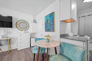 Una cocina moderna con una mesa redonda de mármol, sillas tapizadas en color turquesa y un cuadro de un pavo real.