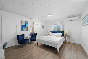 A bedroom with a bed, a chair, a desk, and a window with curtains. - Chic City Retreat 93G (Columbus)