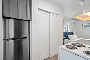 A kitchen with a stainless steel refrigerator, white cabinets, and a white stove.