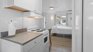 Una cocina compacta con armarios blancos, una estufa y una pequeña encimera.