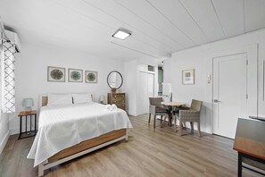 Een slaapkamer met een bed, nachtkastjes, een spiegel en een zithoek met stoelen en een tafel.