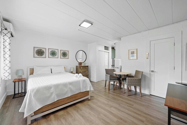 A bedroom with a bed, bedside tables, a dresser, a chair, a small table, and a door.