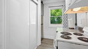 Una cocina con armarios blancos, una estufa y una ventana con vistas al verdor.