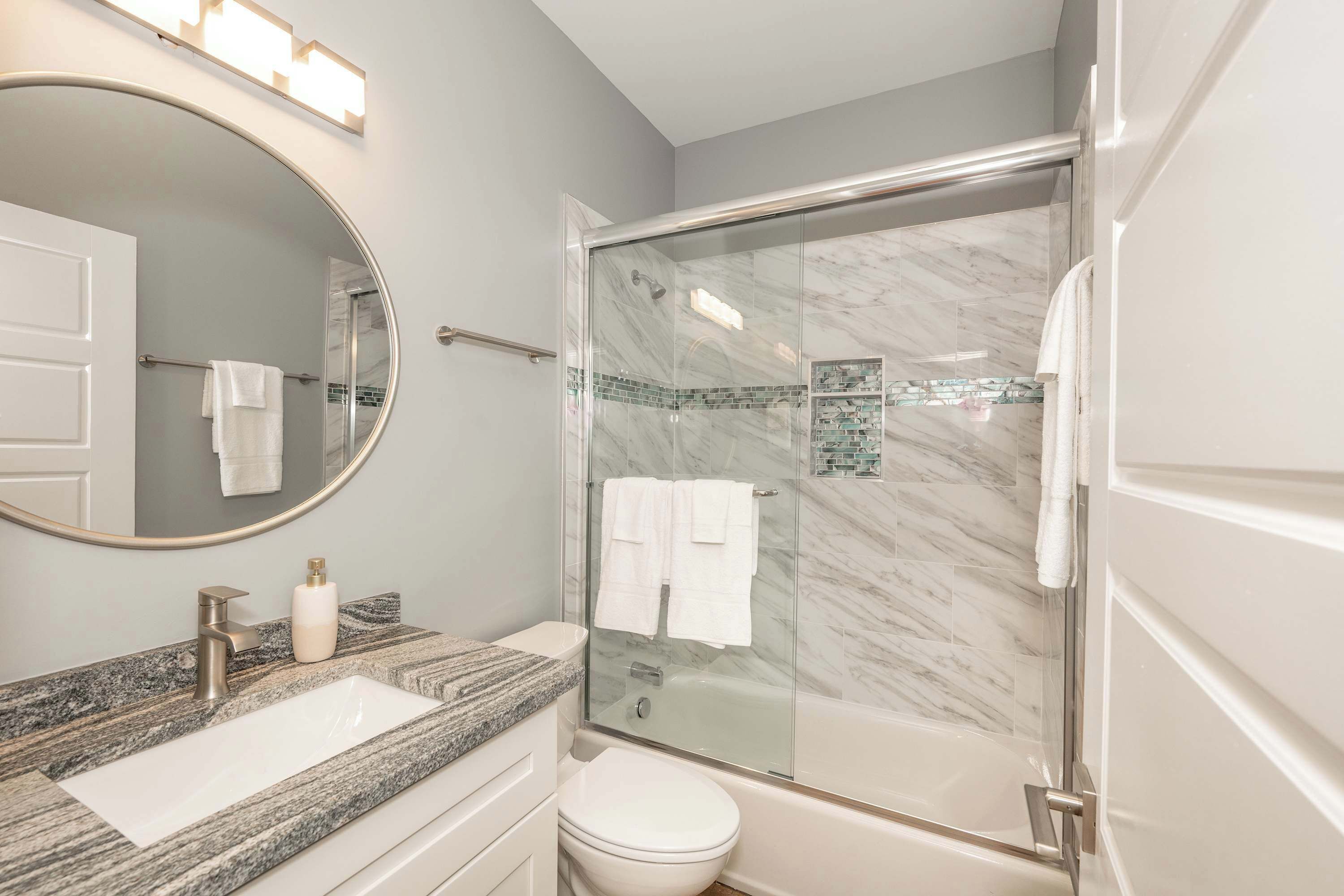 Un baño con ducha de mármol, lavabo e inodoro.