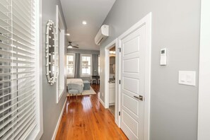 A hallway with wooden flooring, white doors, and a ceiling fan.