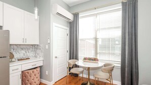 A modern kitchen with white cabinets, a marble backsplash, and a pink ottoman. - Findlay Market Suite 5 – For 2! (Cincinnati)