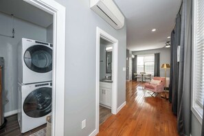 A laundry area with two stacked washers and dryers, a kitchen with white cabinets, and a dining area with a table and chairs.