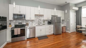 A modern kitchen with white cabinets, stainless steel appliances, and a marble backsplash. - Findlay Market Suite 5 – For 2! (Cincinnati)