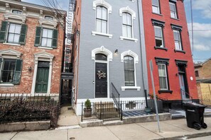 Una hilera de casas urbanas de tres pisos con estilos arquitectónicos diferentes, incluyendo un frente de ladrillo rojo, un exterior gris pintado y detalles blancos.
