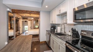 Una cocina moderna con armarios blancos, un microondas de acero inoxidable y una mesa de comedor de madera.