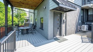 Una terraza techada con mobiliario exterior, una puerta y una unidad de aire acondicionado.