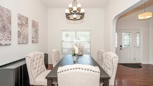 A dining room with a long table, upholstered chairs, a chandelier, and artwork on the walls. - Urban Escape (Cincinnati)