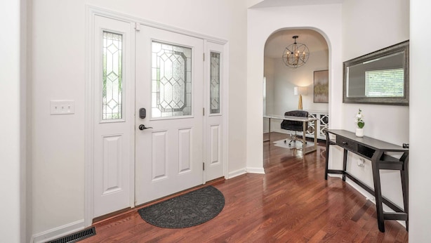A hallway with a white door, a black desk, and a chandelier. - Urban Escape (Cincinnati)