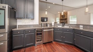 A modern kitchen with dark cabinets, stainless steel appliances, and a built-in wine cooler. - Urban Escape (Cincinnati)